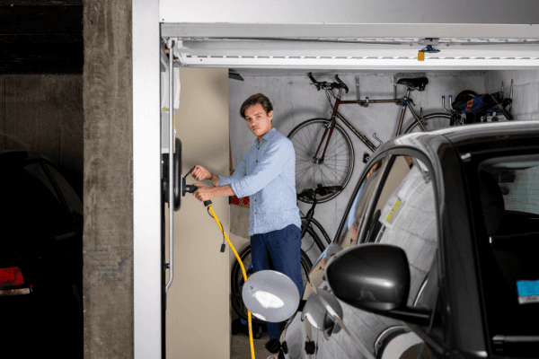homme branche voiture electrique dans parking