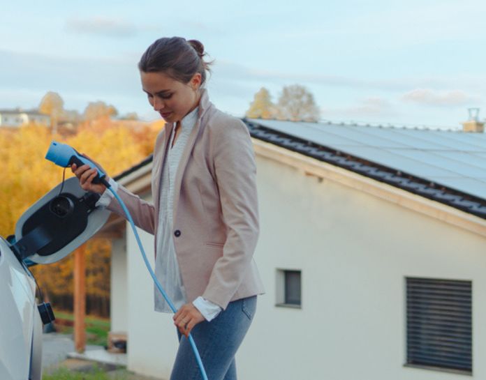 jeune femme charge voiture electrique devant panneau solaire