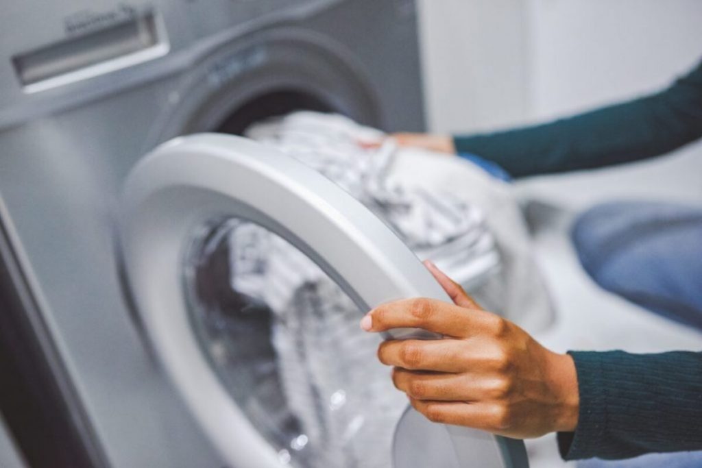 Main femme qui met du linge dans un lave-linge