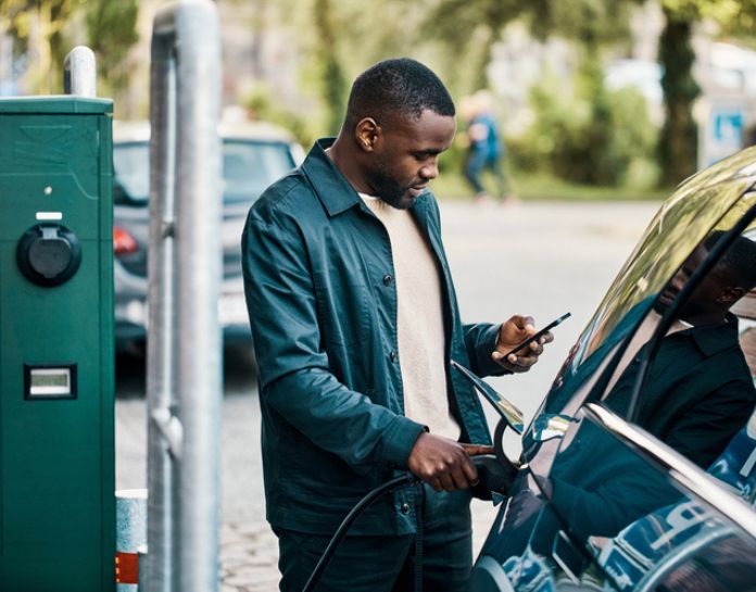 jeune homme charge voiture electrique sur voirie