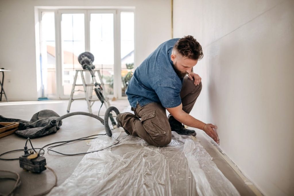 homme ponce mur accroupi logement