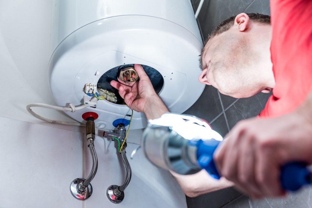 homme reparant chauffe-eau electrique