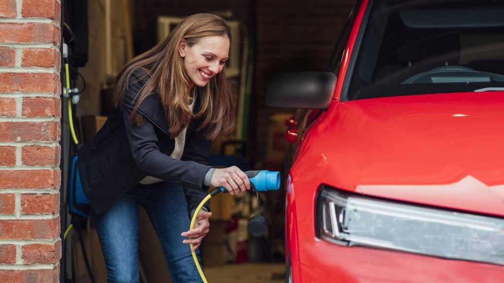 jeune femme charge vehicule electrique dans son garage