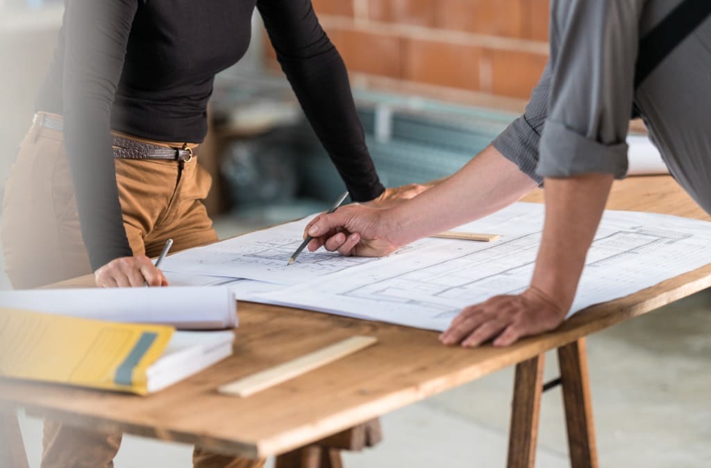 homme et femme planifie travaux autour plan sur table