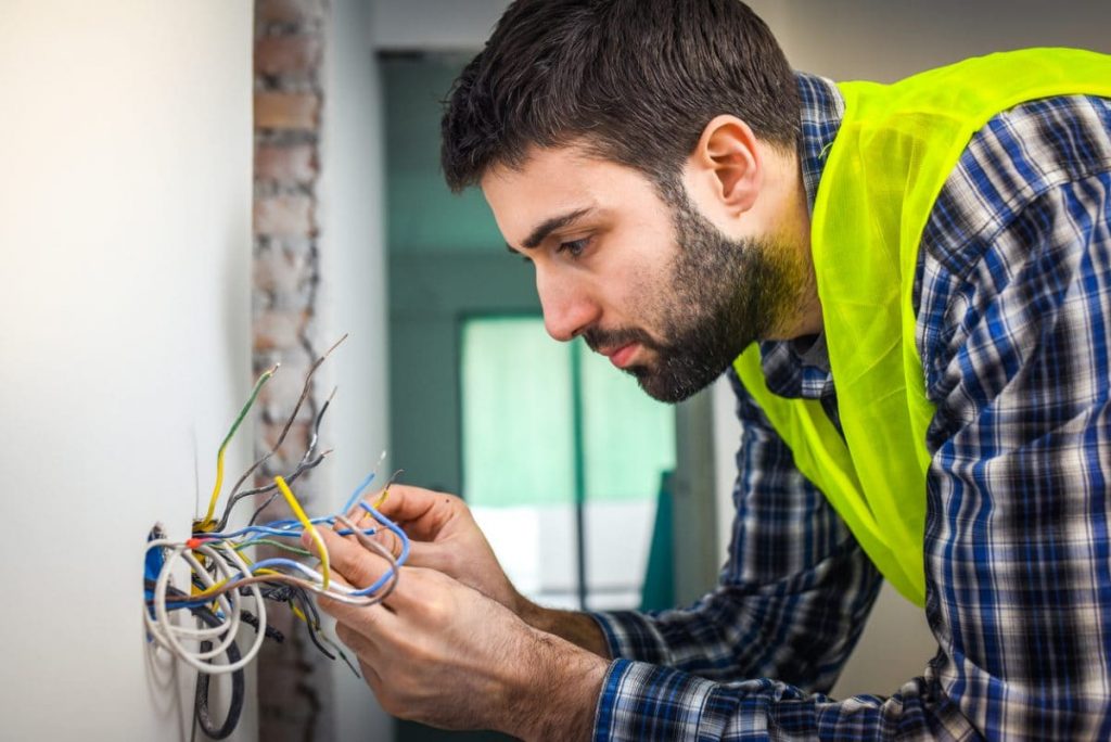 electricien manipule fils prise de courant